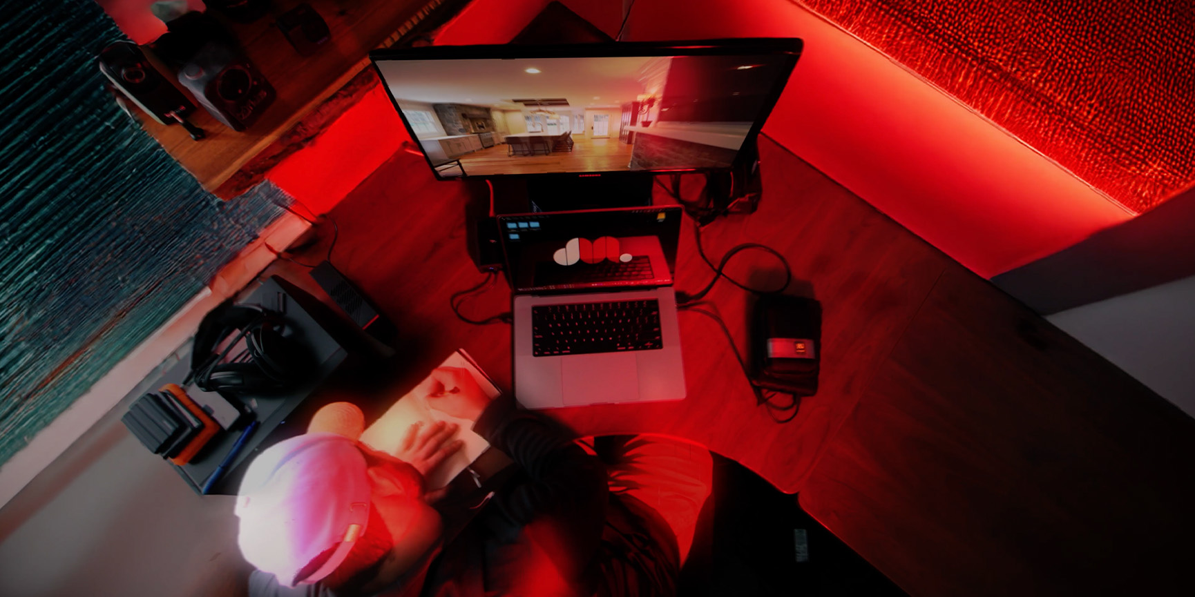 An editor's desk with a vertical 9:16 timeline on one screen and a contractor's phone footage loading on the other.