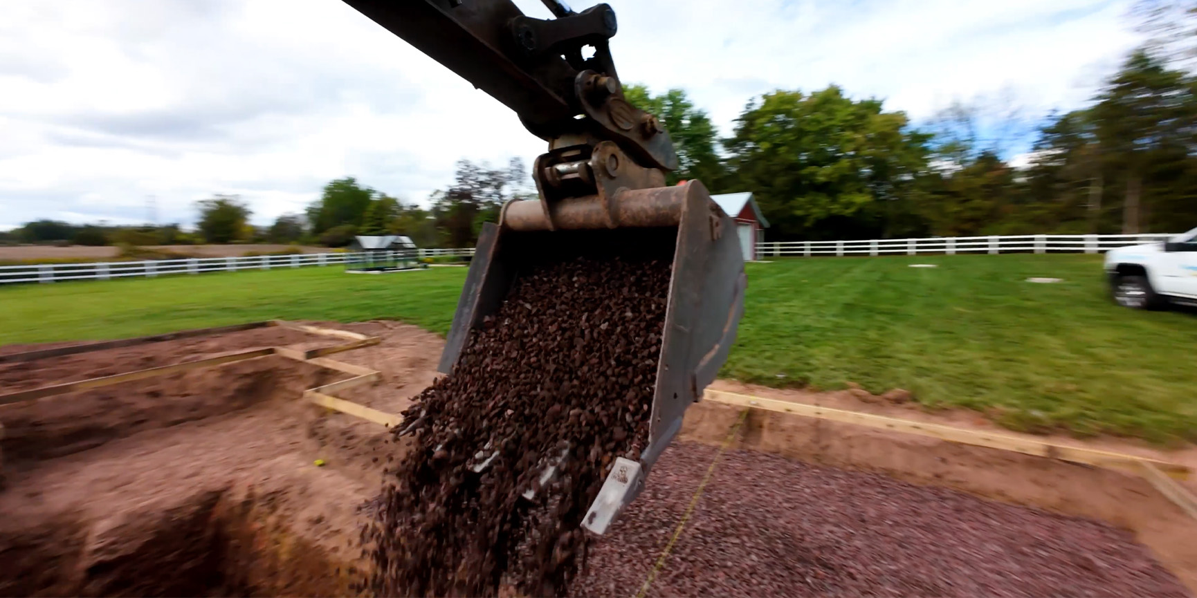 A contractor filming a finished backyard project on a phone while the crew packs up the truck in a Central Texas driveway.